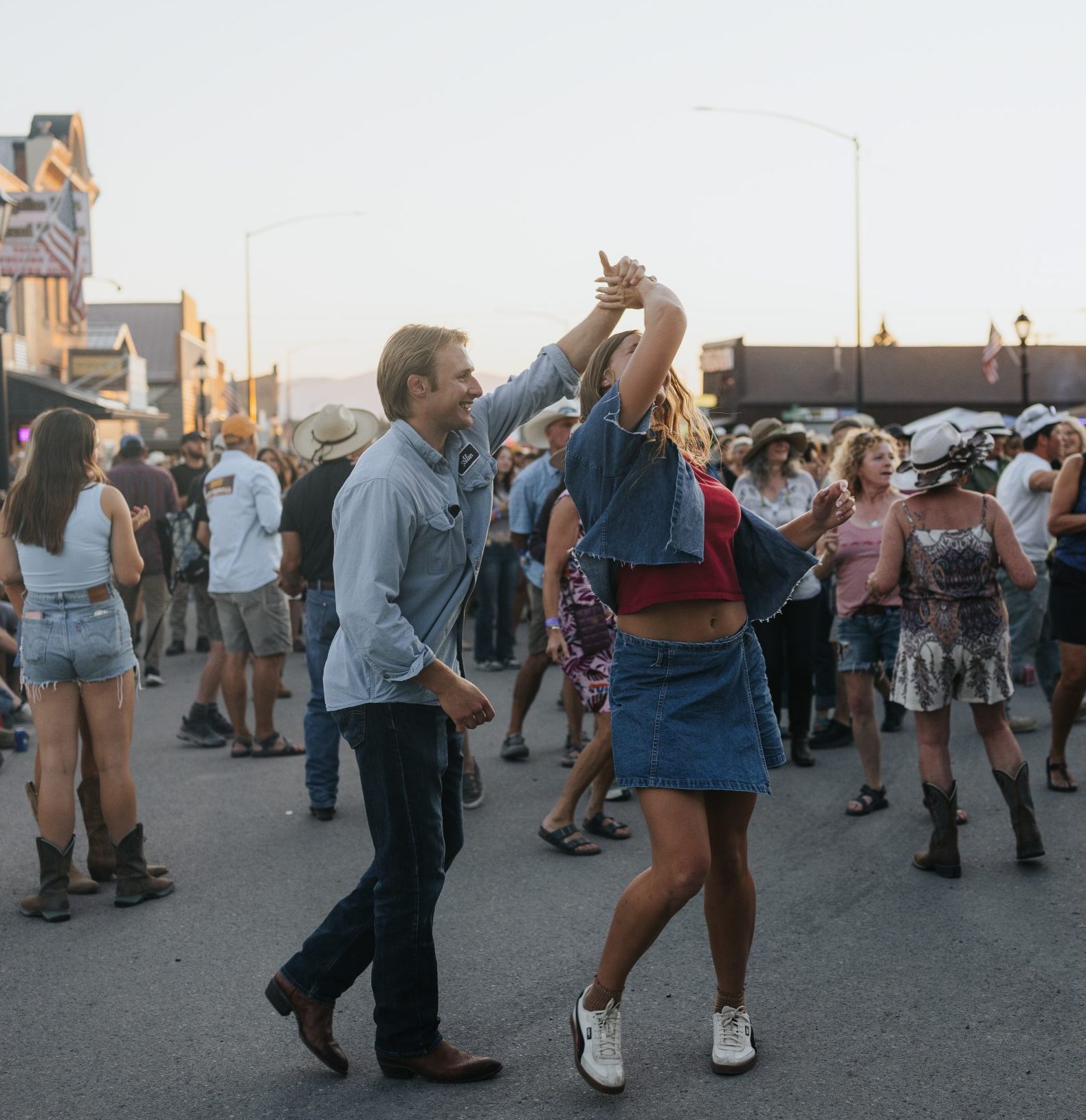 A couple dancing in the street among a crowd at an outdoor festival.